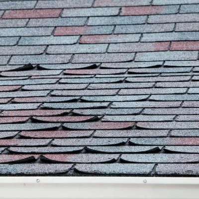 Asphalt shingles separating from a roof.