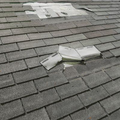 close up view of extremely damaged roof showing the wood underneath both the shingles and the underlayment