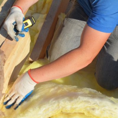 roofer with gloved hands installing new insulation to make new roof more energy sufficient