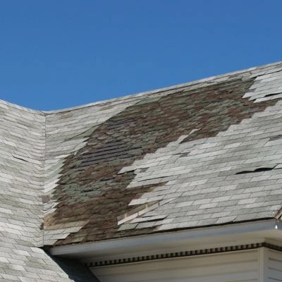 Roof with significant shingle damage exposing the underlayment