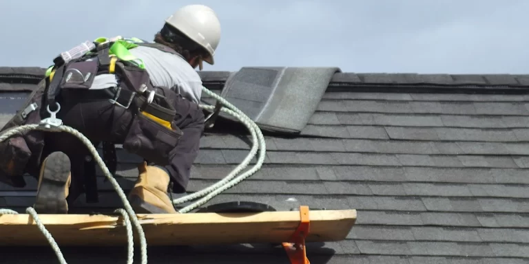 Roofer installing asphalt shingles on a residential roof during repair