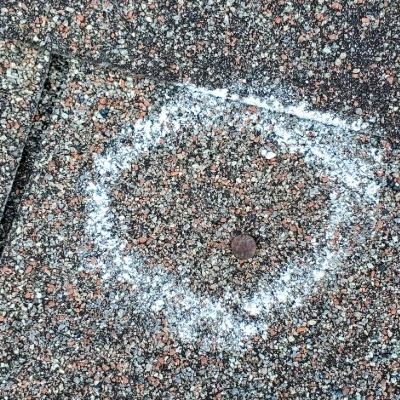 Close-up of asphalt shingle showing significant granule loss indicating roof aging and wear