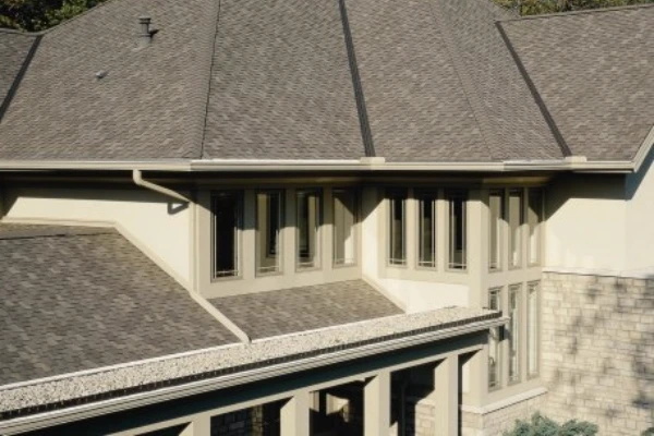 A high-angle view of a complex roofing system with multiple gables, clean valleys, modern architectural shingles and new gutters.