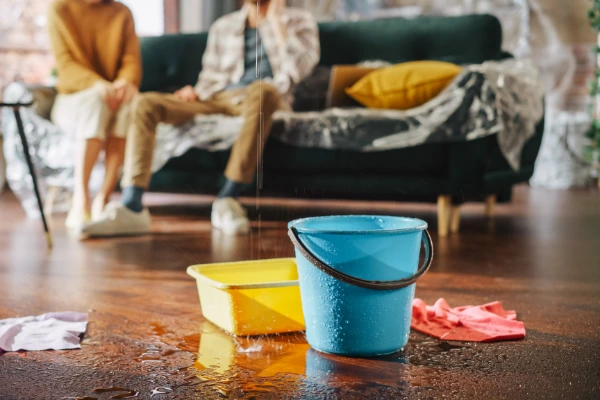 Buckets catching water from an active roof leak inside a home during a storm