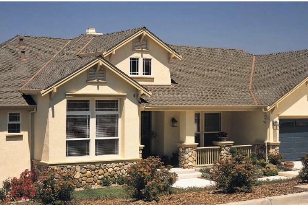 Presidential Chaparral Cedar CertainTeed shingle roof on a tan craftsman-style home with stone accents, and covered front porch